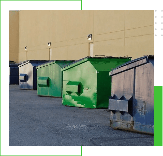 A row of green and gray garbage cans in front of a building.