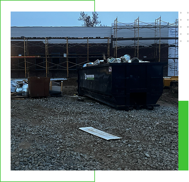 A dumpster sitting in the middle of a gravel lot.